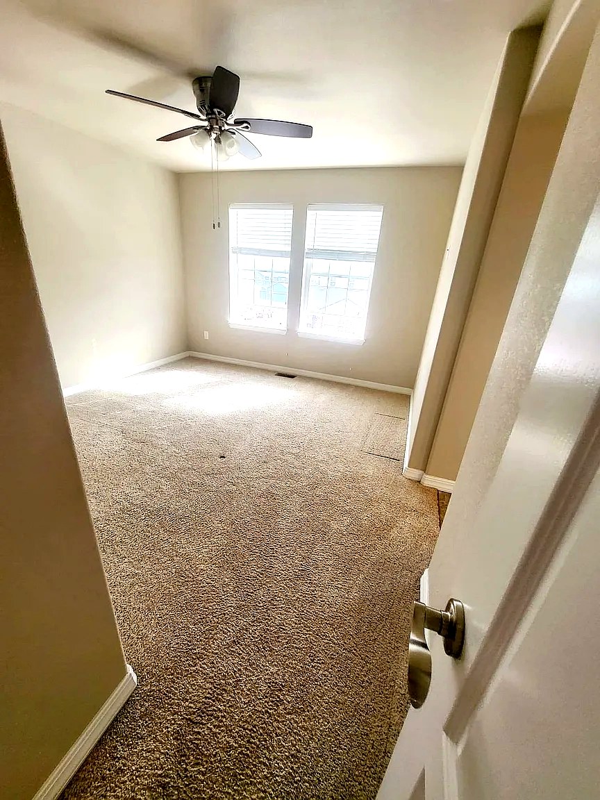 Second bedroom with ceiling fan and large windows