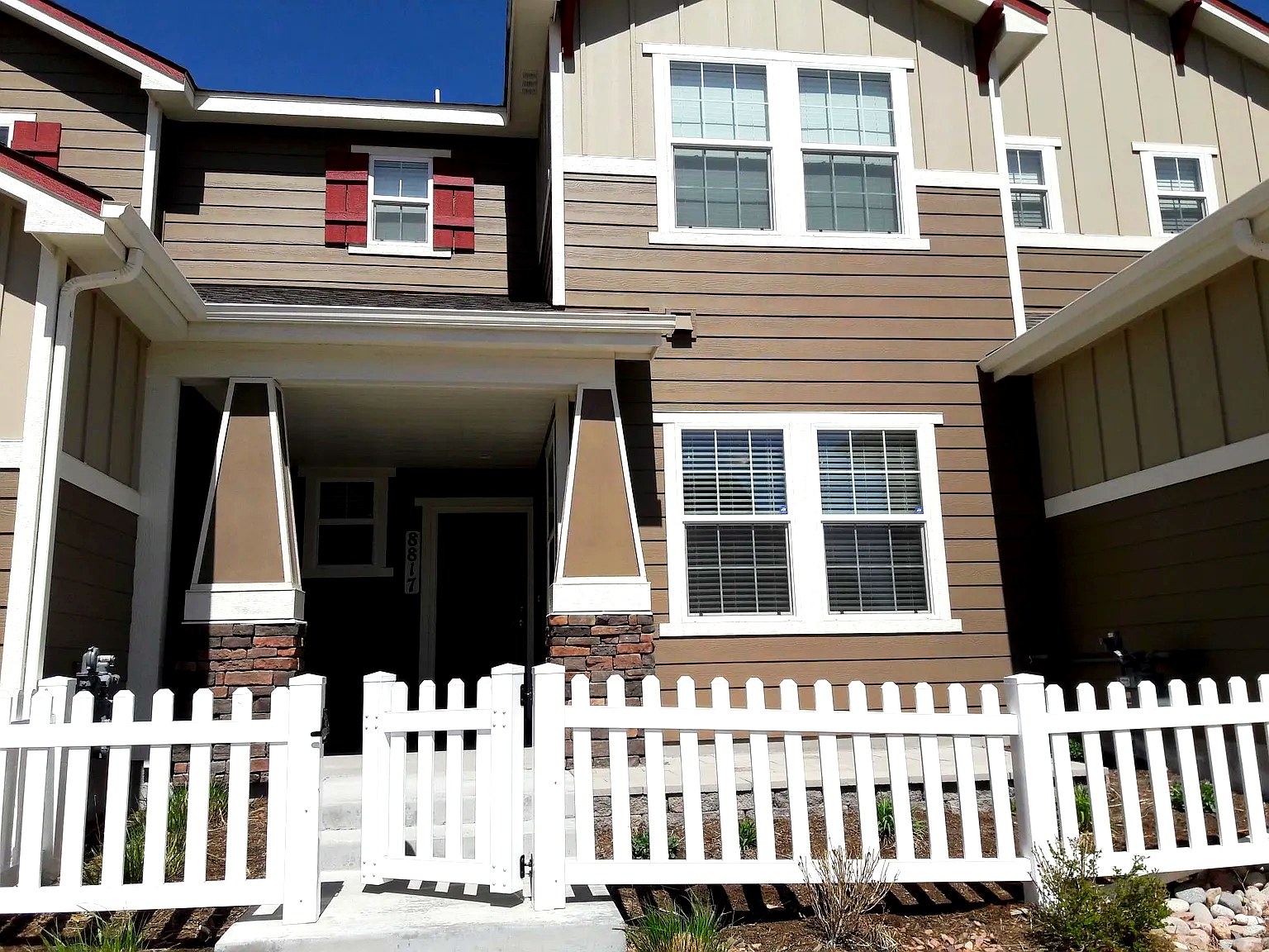 Front exterior of Bella Flora with white picket fence and red accents