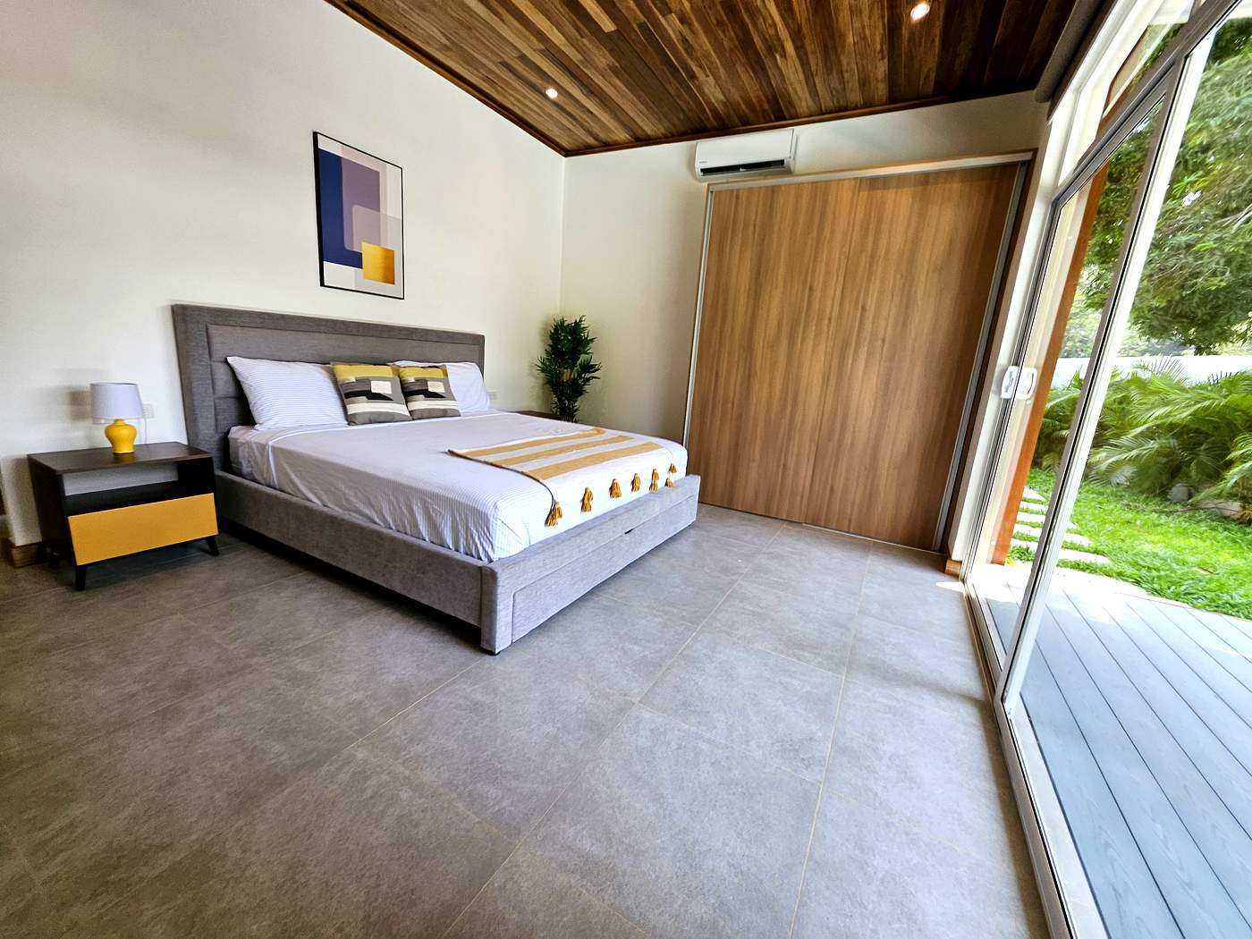 Second bedroom with king bed, yellow accents, and garden door