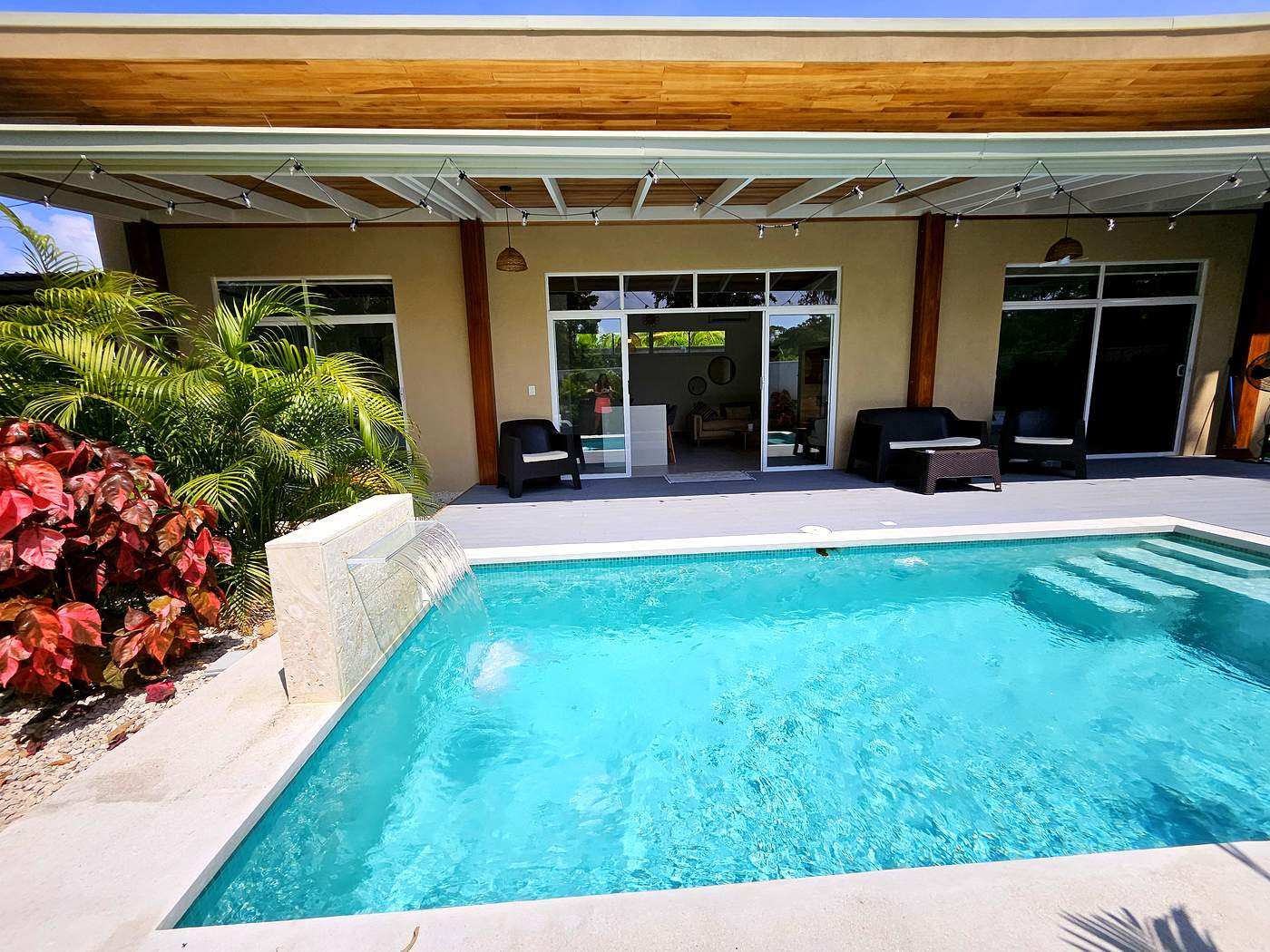 Private pool and house exterior with waterfall feature and tropical garden