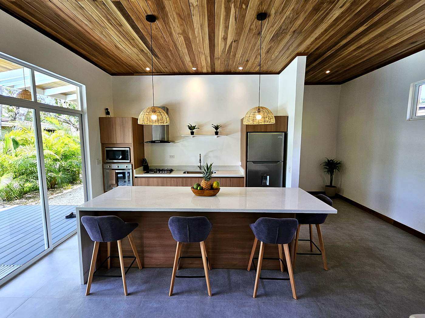 Open-plan kitchen with quartz island and rattan pendant lights