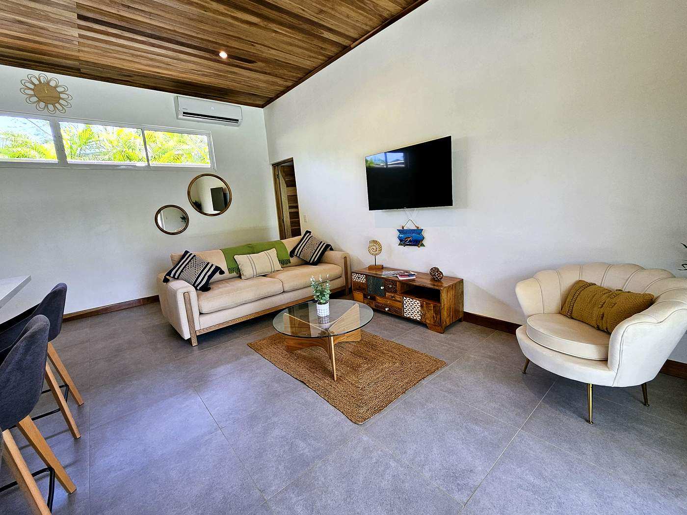 Living room with cream sofa, round mirrors, and TV