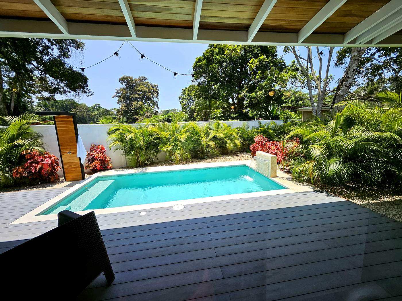 Private pool from covered terrace with string lights