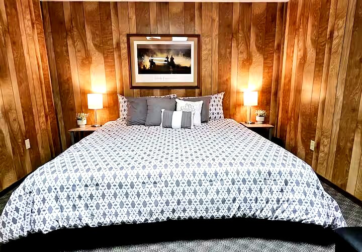 Master bedroom with queen bed, geometric bedding and wood paneling
